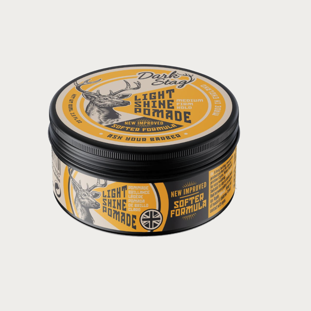 A round metal tin of Dark Stag Light Shine Pomade, featuring a black lid and base with a yellow and black label, set against a light gray background.