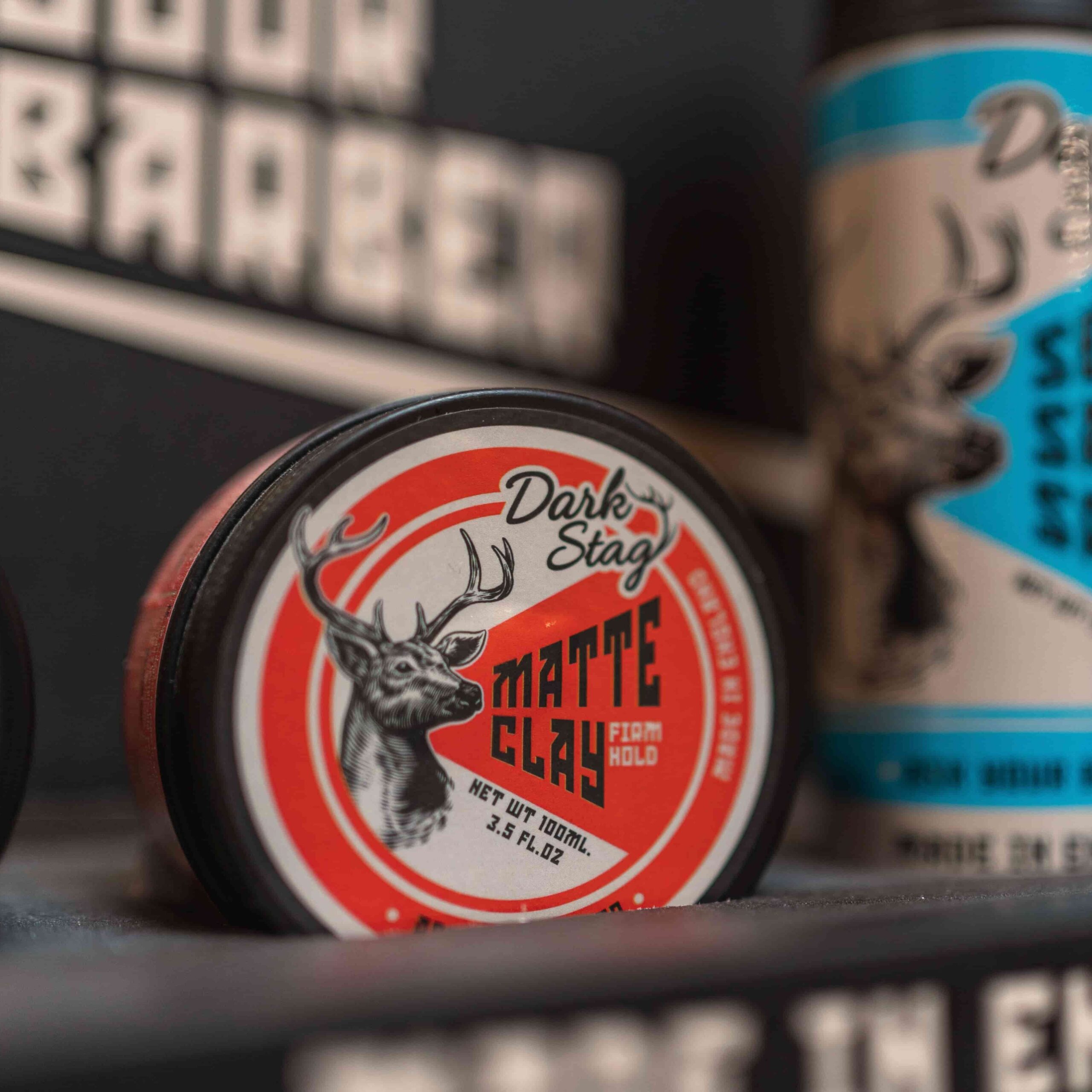 Jar of Dark Stag Matte Clay with a deer logo on a shelf.